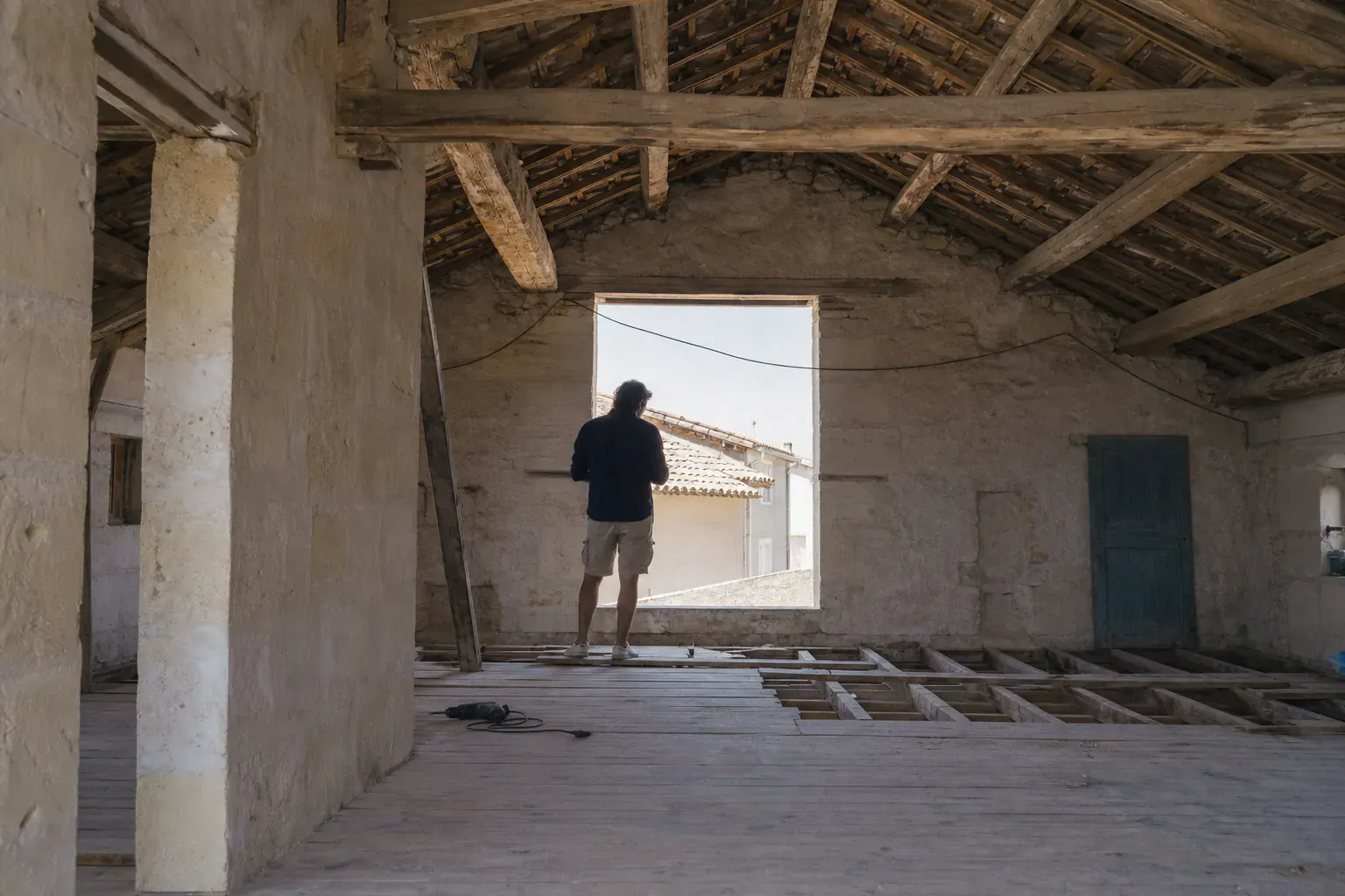 Comble non aménagé, structure de toit apparente et aucune isolation entre les solives, jour passant par une tuile de verre