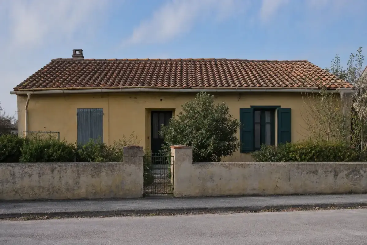 Maison individuelle modeste du Midi vue de la rue, toute sa toiture de terre cuite tenant dans le cadre