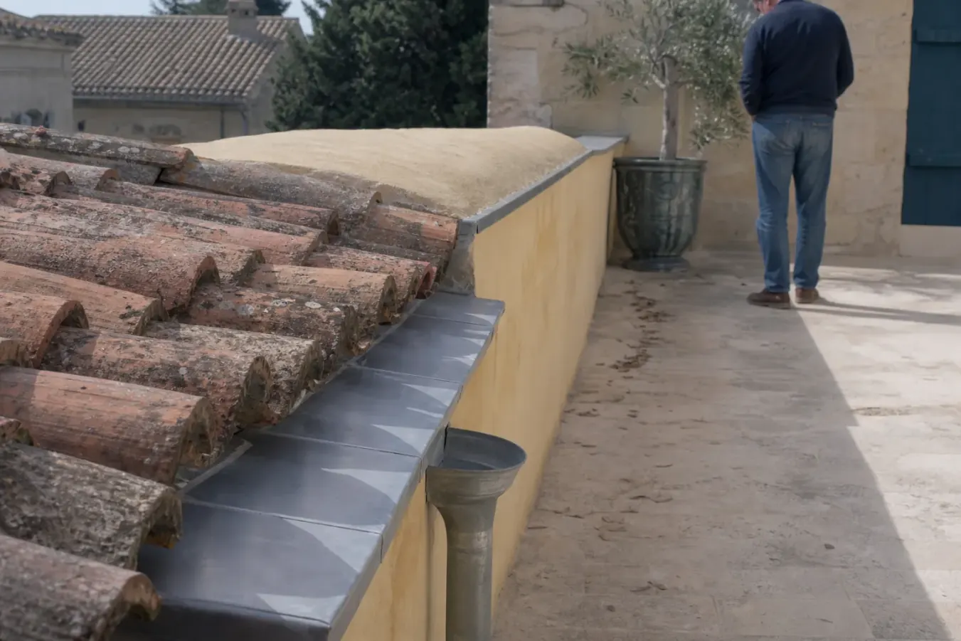 Chéneau de zinc reconstruit derrière un acrotère, soudures visibles, naissance posée et tuiles recoupées au bord