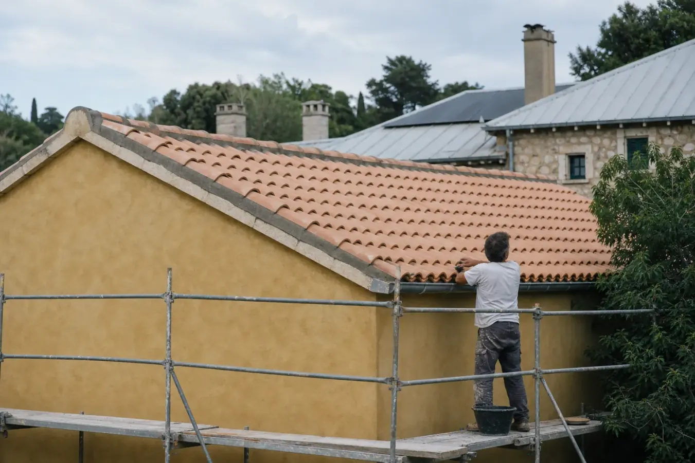 Toiture refaite en tuiles canal de terre cuite, rangs réguliers et faîtage fraîchement scellé au-dessus d’une façade ocre